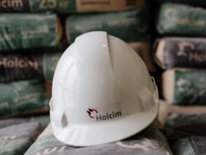 Компания Holcim выпускает линейку универсальных сухих смесей, подходящих как для ручного, так и механизированного нанесения В строительный мир стремительно пришли технологии механизированного нанесения сухих смесей. При производстве таких работ используются специальные растворонасосные станции. Однако и без ручного нанесения смеси в строительстве не обойтись. Компания Holcim выпустила на рынок универсальные смеси, которые применяются при устройстве наливных полов, черновой отделке стен внутри здания и его фасада как машинным, так и ручным способом. Универсальность сухих смесей Holcim достигается благодаря качественно подобранному составу. К смесям, которые используются для механизированного способа нанесения, предъявляются дополнительные требования: они должны успеть приготовиться в машине. И компания Holcim разработала материалы, которые полностью этому критерию соответствуют. В штукатурке Holcim используется песок мелкой фракции 0,63 мм, что позволяет заметно снизить износ штукатурной станции. Кроме того, раствор легко проходит по шлангам и распределяется на поверхности. Штукатурка равномерно ложится на стены, что в дальнейшем облегчает чистовое выравнивание и снижает последующий расход шпаклевки. Повышает эффективность и оптимальный состав смеси. Наличие в нем заполнителей и полимерных добавок придает раствору достаточную вязкость (текучесть) и пластичность. А это, в свою очередь, помогает штукатурке держаться на стене после нанесения, а также полностью нивелирует риск закупорки шланга штукатурной станции. Подготовленная в ней смесь сохраняет жизнеспособность на протяжении двух часов, что позволяет оптимизировать все технологические процессы и уменьшить вероятность досрочного схватывания штукатурки. «Мы много лет работаем со смесью Holcim, – рассказал владелец компании «1000TURKA» Алексей Сон. – Она и на больших слоях хорошо держится, и прочность у нее хорошая, и расход радует. Я вообще минусов не вижу, одни плюсы. Аналоги у этих смесей, конечно, есть. Но аналоги с точки зрения соотношения цены/качества и удобства нанесения мне неизвестны». Наливной пол Holcim также подходит для механизированного нанесения. Благодаря автоматизированному дозатору воды, которым снабжена механизированная станция, приготовленная в ней смесь получается однородной, а выходящий из шланга раствор не расслаивается. Таким образом, исключается человеческий фактор, а наливной пол получается стабильным по качеству и прочным. К тому же раствор самовыравнивающийся, что значительно облегчает и ускоряет монтаж пола на больших площадях. При этом оптимальные сроки схватывания позволяют без лишней спешки обработать полученный слой. В результате получается идеально ровная и прочная на сжатие (не менее 15 МПа) поверхность, которая подходит не только для новых зданий. Такой пол будет надежно служить и в старых домах, поэтому его используют при ремонте вторичного жилья, в больницах и административных помещениях. В смеси для наливного пола также используется песок мелкой фракции 0,63 мм, что уменьшает износ механической станции. Испытания смесей Holcim, проведенные совместно с ведущим производителем растворонасосной техники Putzmeister, подтвердили качество материалов компании в использовании их методом машинного нанесения. «По отзывам наших клиентов, работающих на “Миксах”, идет большое количество положительной информации о качестве цемента компании Holcim. Они отдают предпочтение именно этому продукту», – рассказал представитель компании Putzmeister Виктор Петриков. Строители знают, что механизированный способ отделочных работ подразумевает аналогичную ручному последовательность действий. Работы начинаются с подготовки основания, то есть заделки трещин, очистки и шлифования поверхности, грунтования. И только затем используются машины. За счет слаженной работы и высокой компетенции бригады, а также применения механизированного способа удается повысить производительность в 4–5 раз, что значительно снижает сроки и дает возможность производить работы даже на самых сложных объектах.